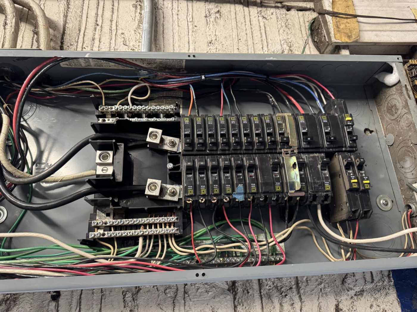 Older residential panel open for diagnosis — breakers and wiring before protection upgrades