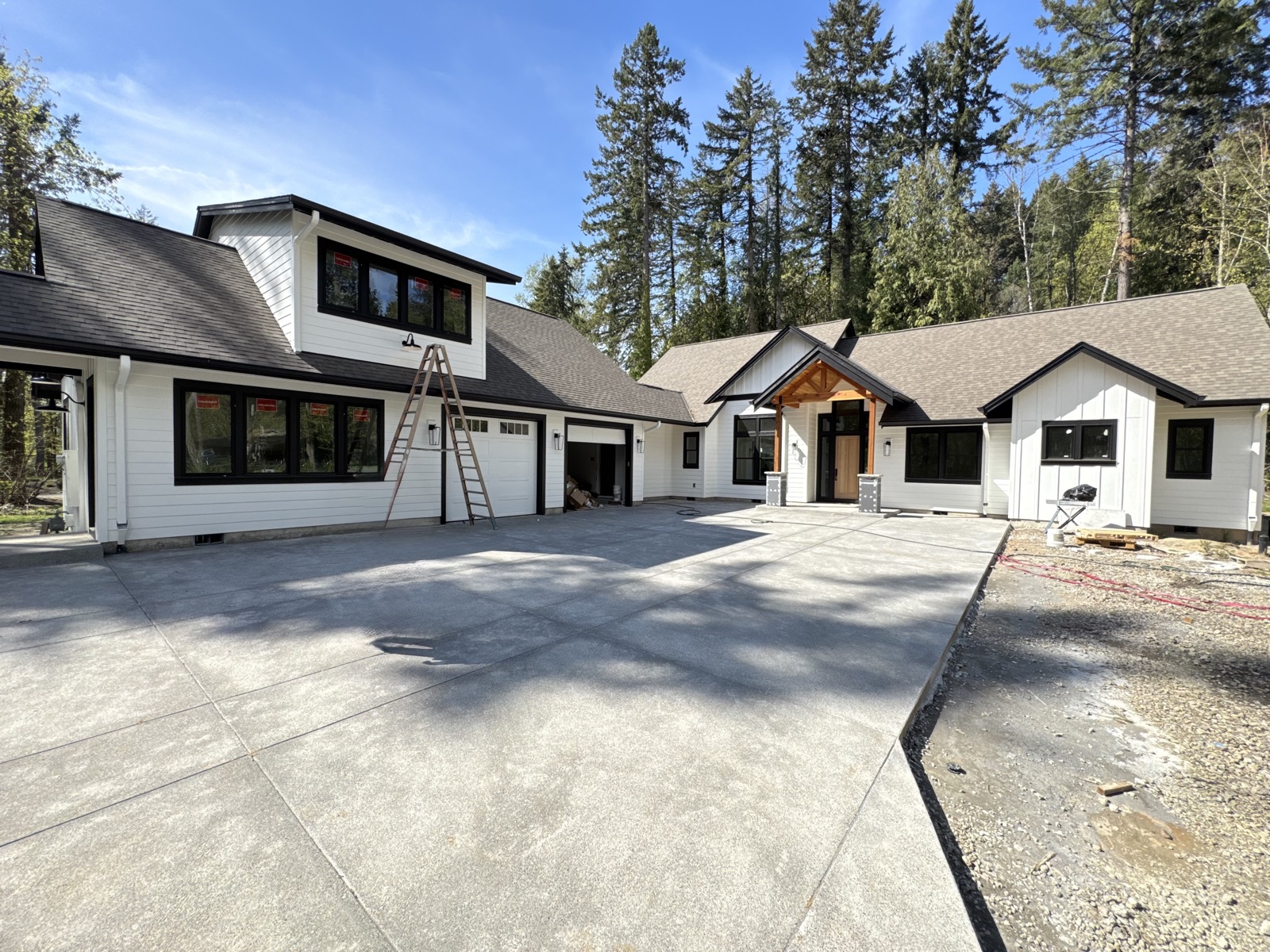 Custom modern farmhouse home in Wilsonville — white board-and-batten siding, black trim, timber-post entry, with attached in-law suite